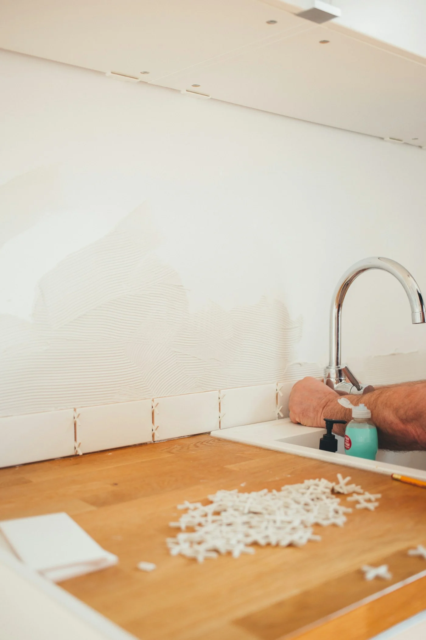 Person working at a kitchen sink and tiled counter