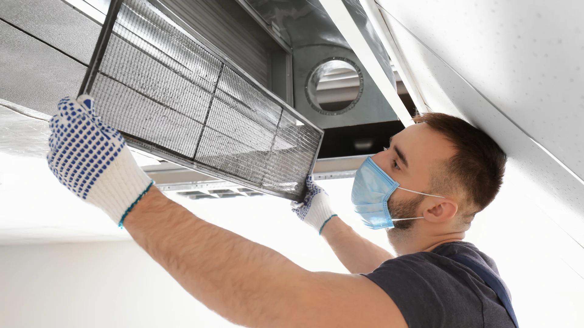 Technician cleaning overhead ductwork
