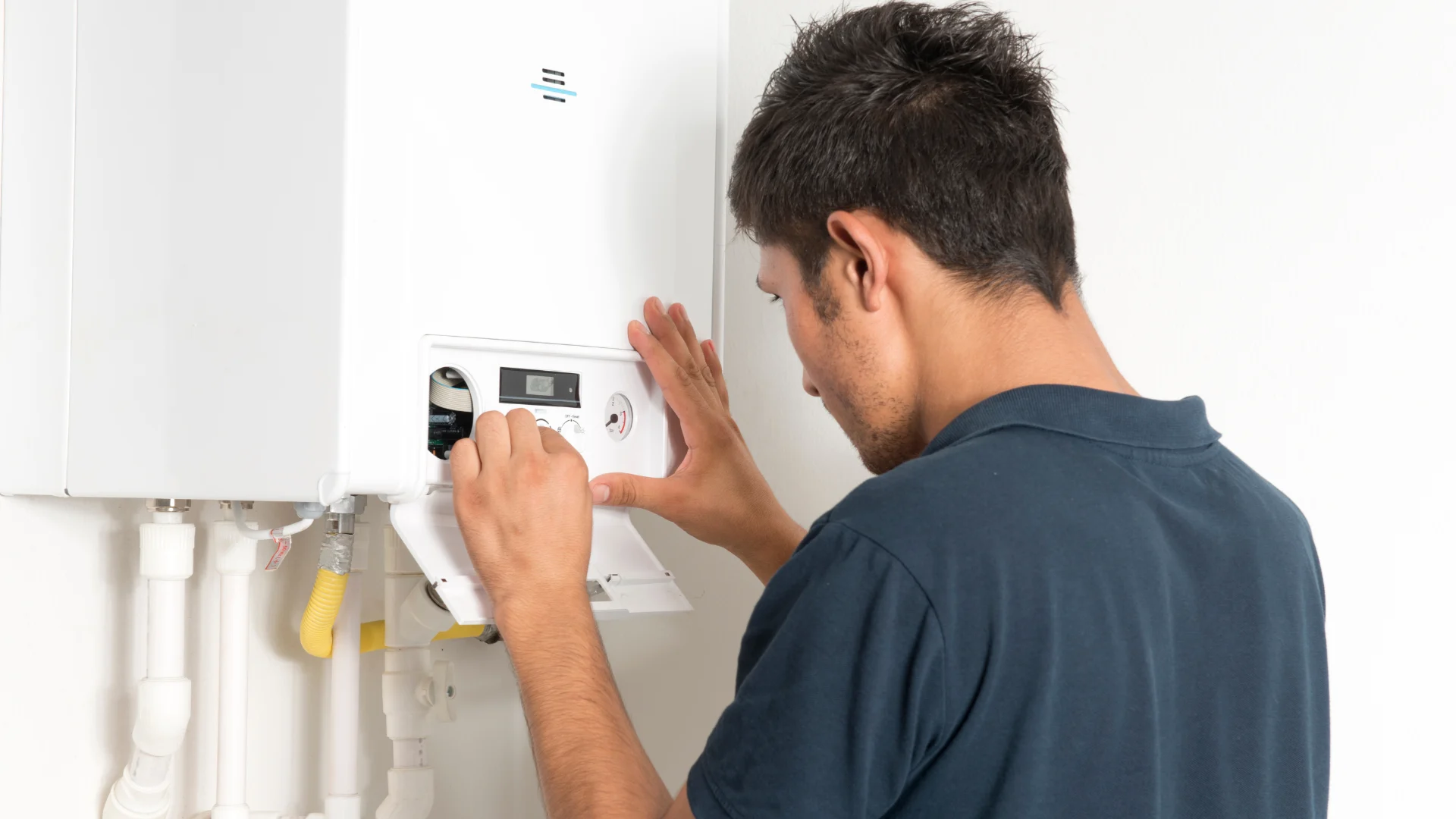 Technician inspecting a wall-mounted boiler